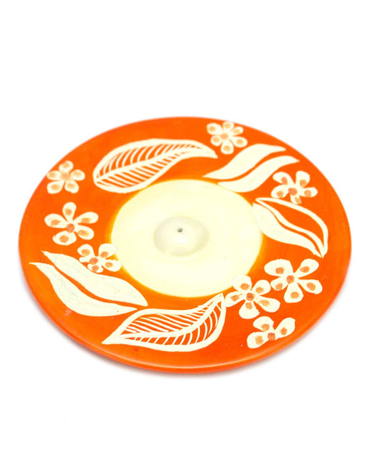Orange floral soapstone incense holder on a wooden surface, ready to hold an incense stick, handcrafted in Kenya.