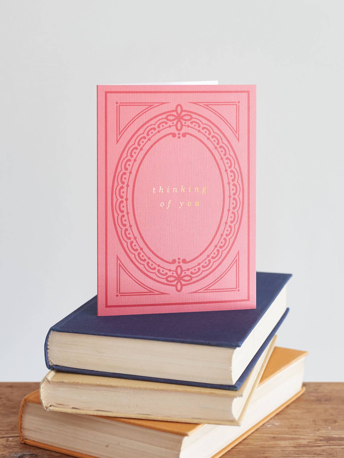 Close-up of 'Thinking of You' card, showing hot foil text and pink buckram texture, paired with a natural recycled kraft envelope, made in the UK.