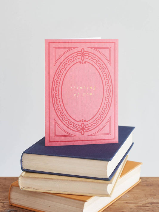 Close-up of 'Thinking of You' card, showing hot foil text and pink buckram texture, paired with a natural recycled kraft envelope, made in the UK.