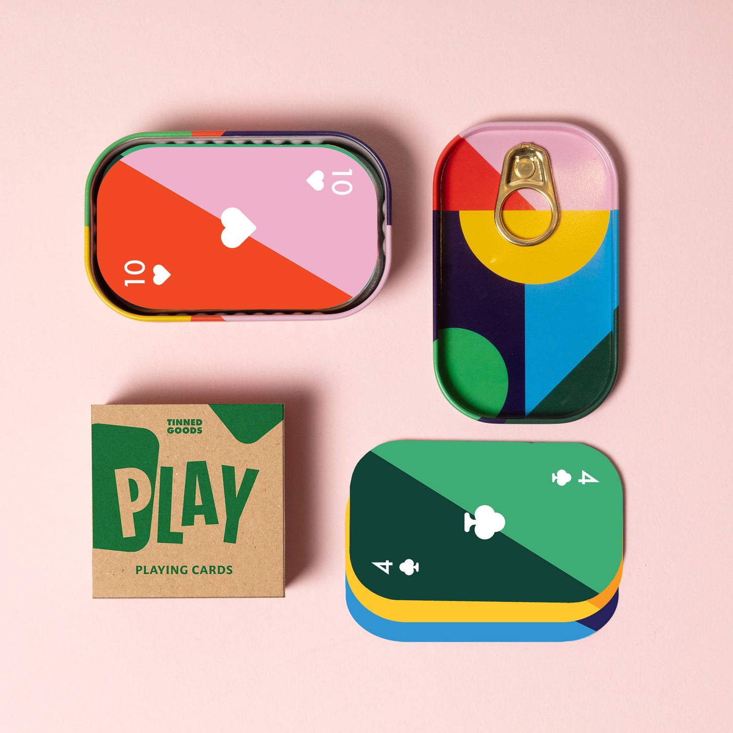 Colorful playing card tins and a box labeled 'Play' on a pink background