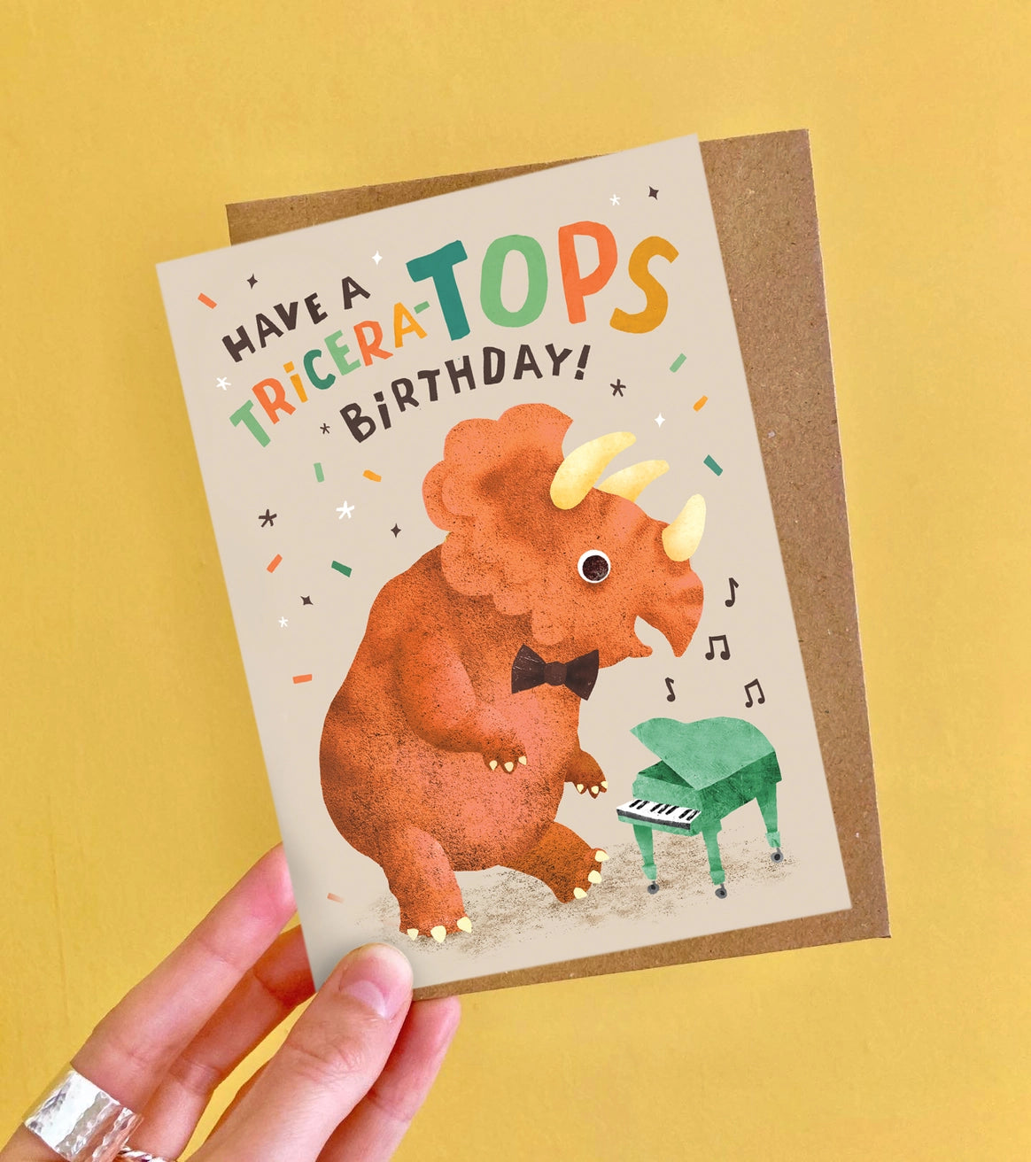 Birthday card with triceratops illustration and text on a yellow background