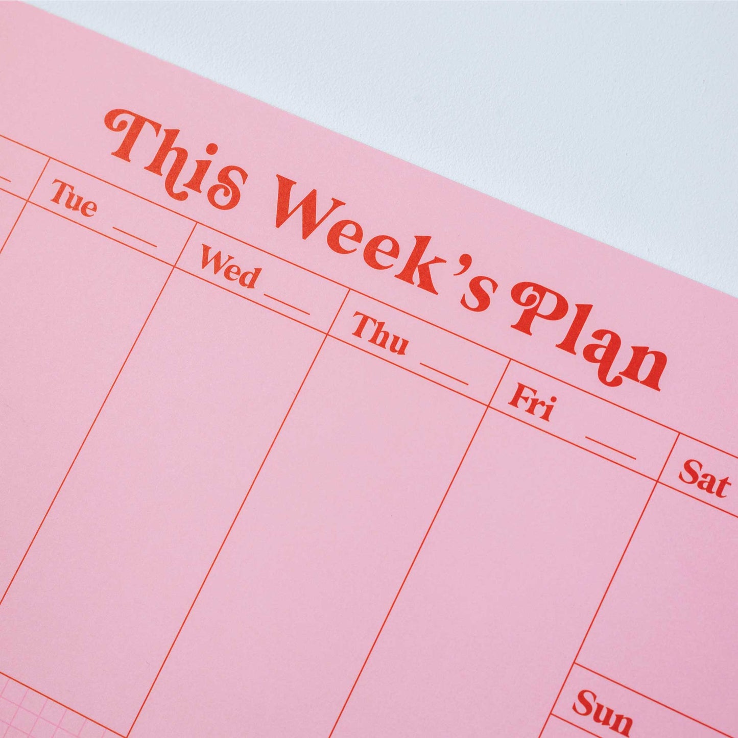 Side view of the A4 Pink & Red Weekly Planner Pad, showing the 52 tear-away pages and cardboard backing.