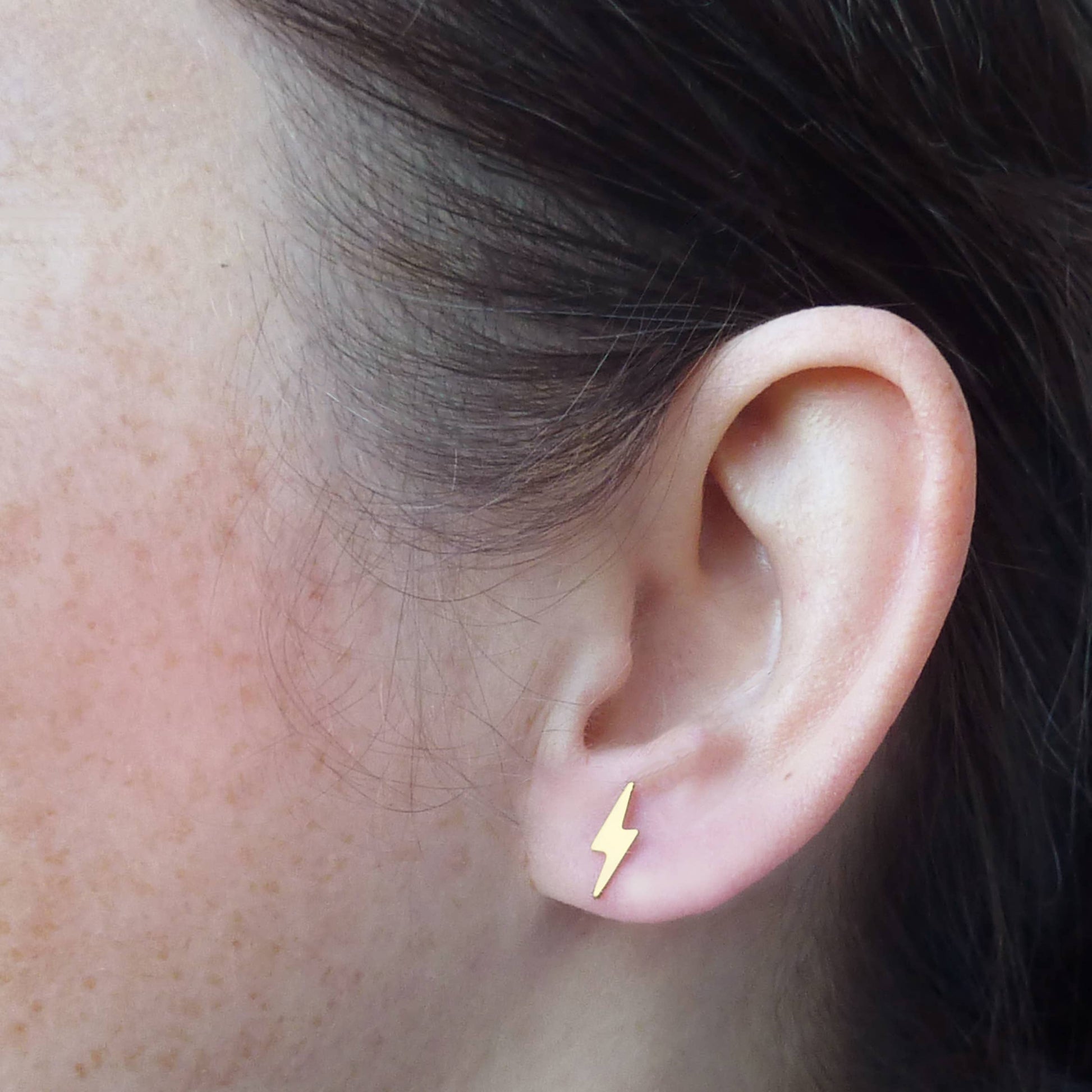 Minimalist gold lightning bolt earrings on sustainable packaging