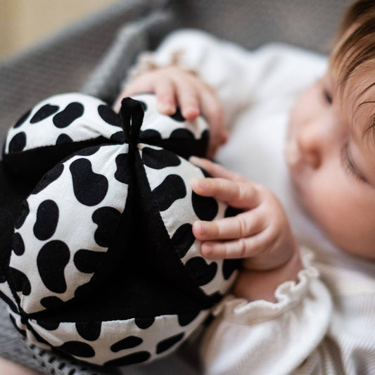 Sensory grasp ball in Dalmatian print by Etta Loves, 12cm diameter, made from organic cotton with segments for grasping and a central bell for sensory play.