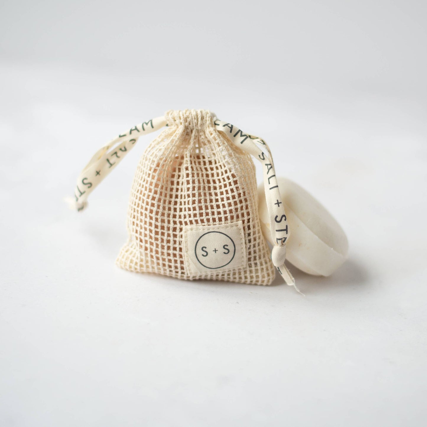 Natural cotton storage bag hanging with shampoo bar drying inside