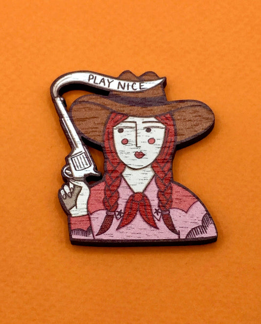 Cowgirl wooden pin brooch with 'Play Nice' message, original illustration by Su Owen, made from sustainable walnut wood, secure metal bar back, UK-made.
