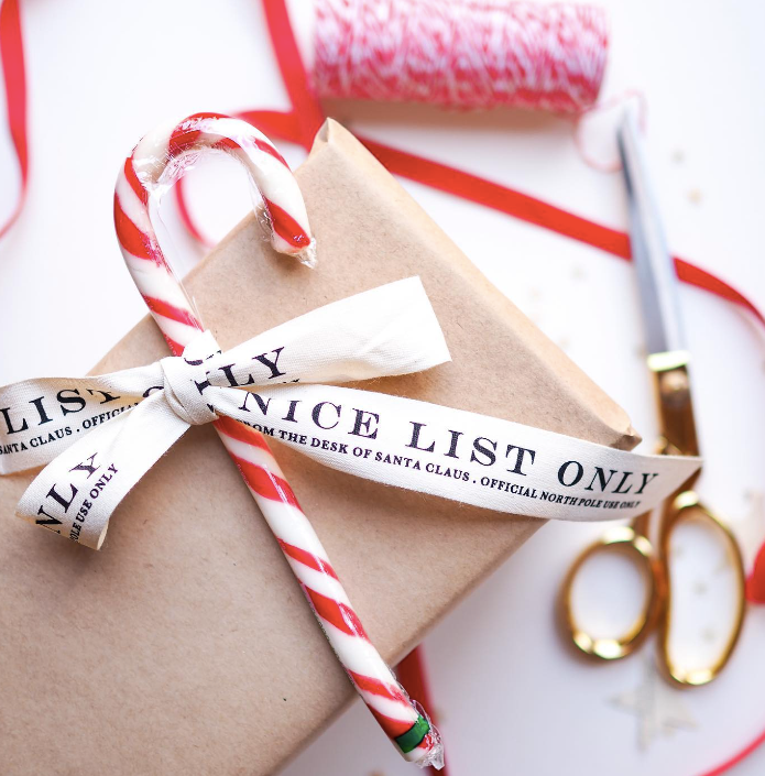 Gift wrapped in brown paper with candy canes and a 'Nice List Only' ribbon on a white background.
