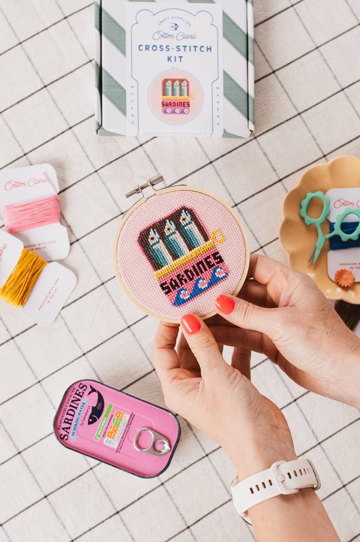 Sardines Cross Stitch Kit for beginners, featuring a 4-inch wooden hoop, coloured Aida fabric, embroidery thread, and eco-conscious packaging. Made in UK.