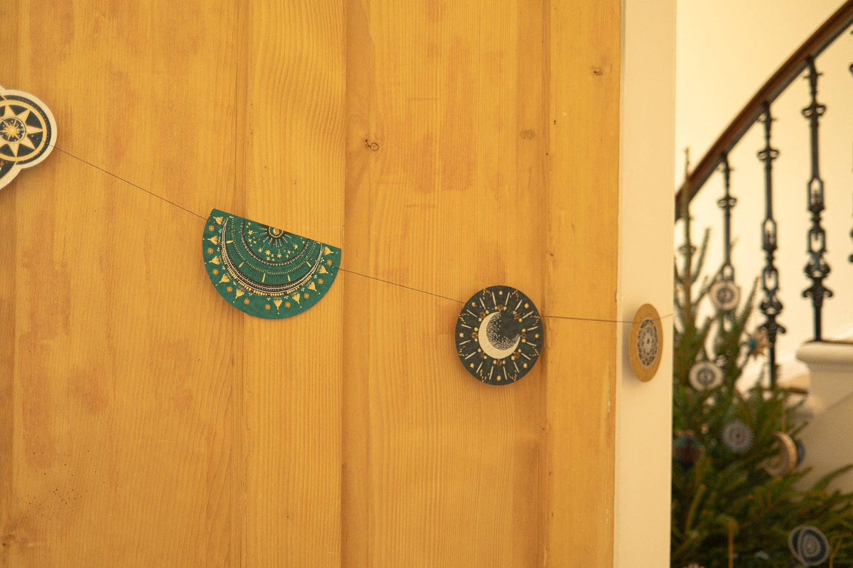 Deep blue and teal paper garland hanging on a neutral wall