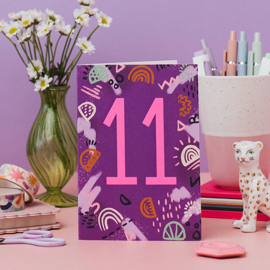 Close-up of neon pink '11' on eco-friendly birthday card, showing abstract design detail