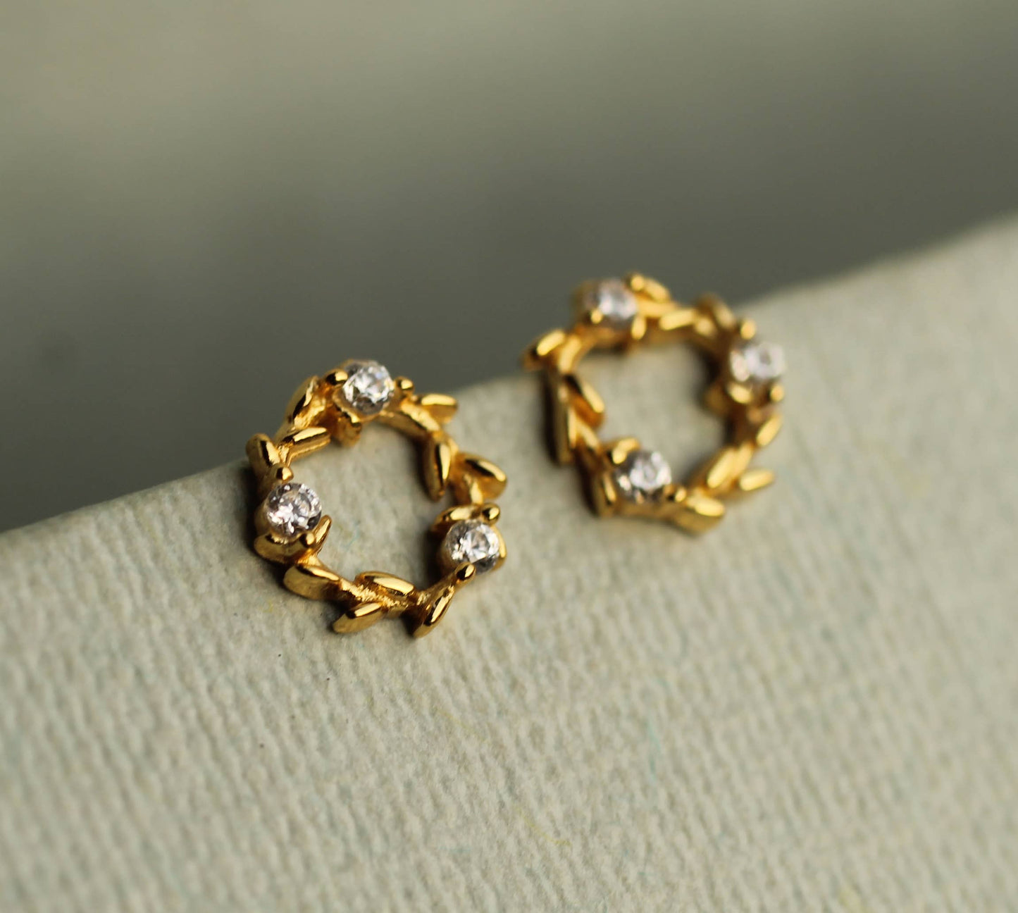 These charming and unusual stud earrings feature a miniature laurel leaf design, with cubic zirconia crystals formed to create a fluid, Art Nouveau inspired design. The earring posts and butterfly backs are gold plated 925 sterling silver. 