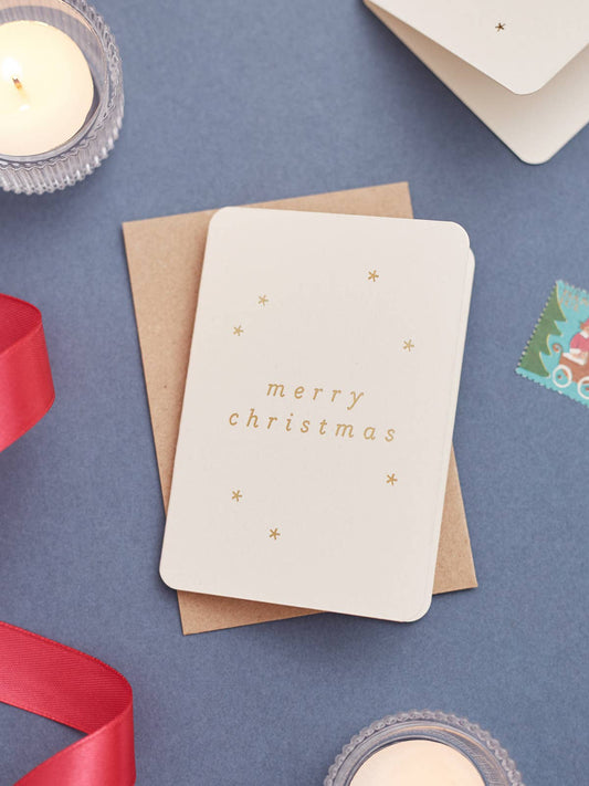 Mini Merry Christmas Card with gold hot foil stars and ‘Merry Christmas’ on recycled coffee cup card, paired with a recycled kraft envelope.