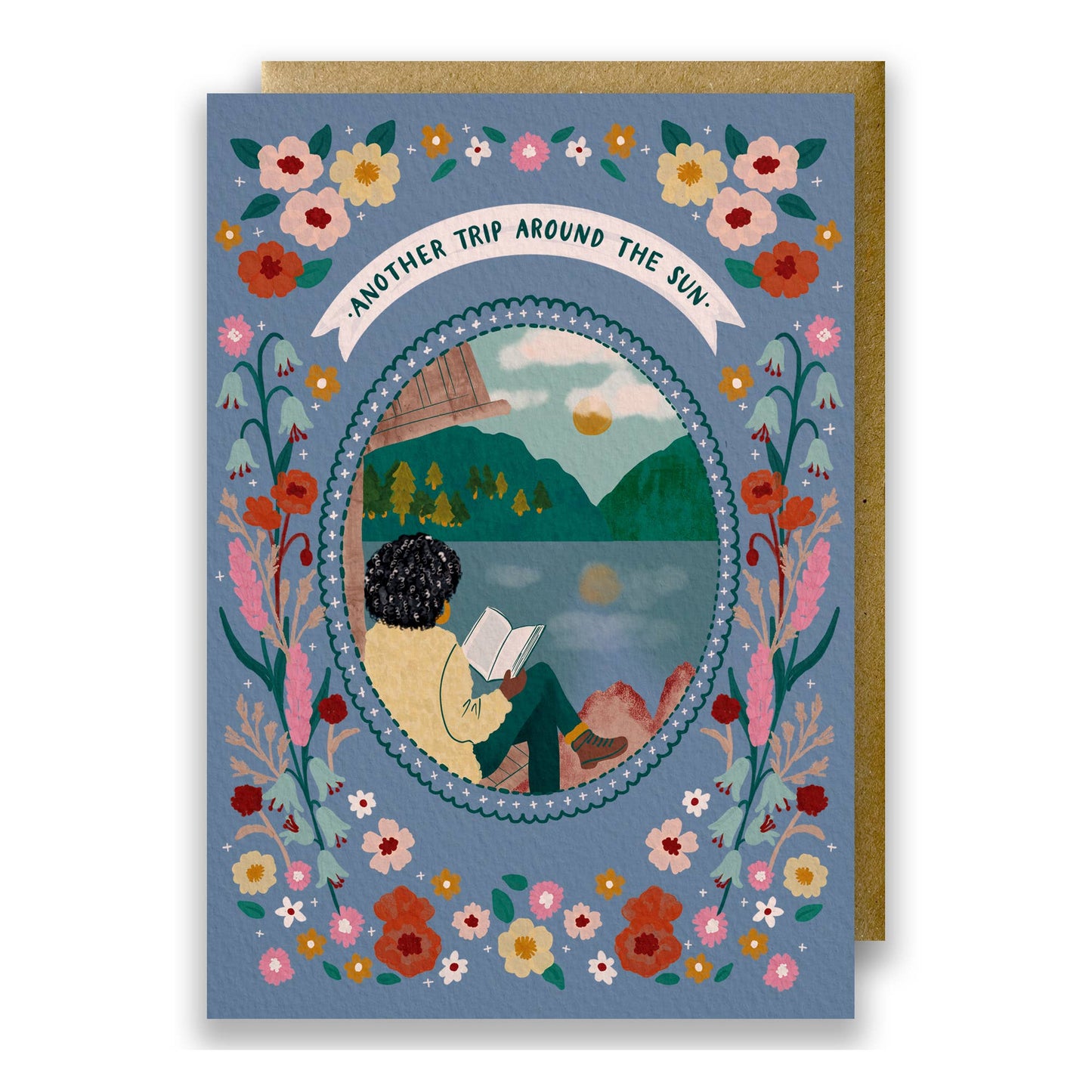 Wild Adventure Another Trip Around The Sun birthday card featuring a woman reading by a lakeside cabin