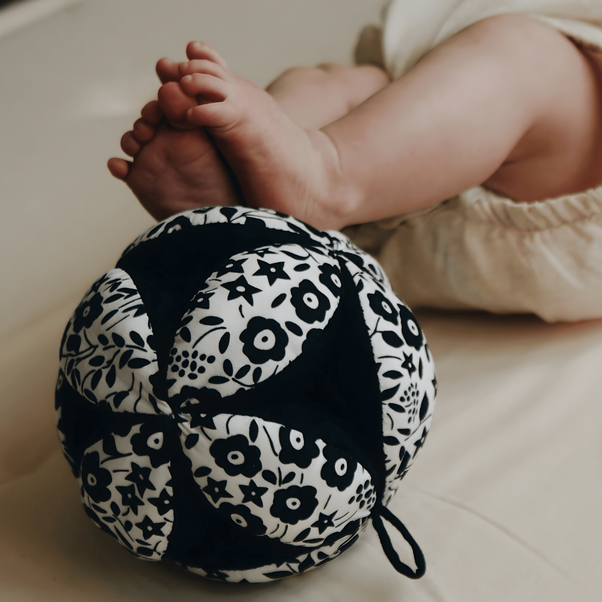 Newborn baby holding the black and white sensory grasp ball
