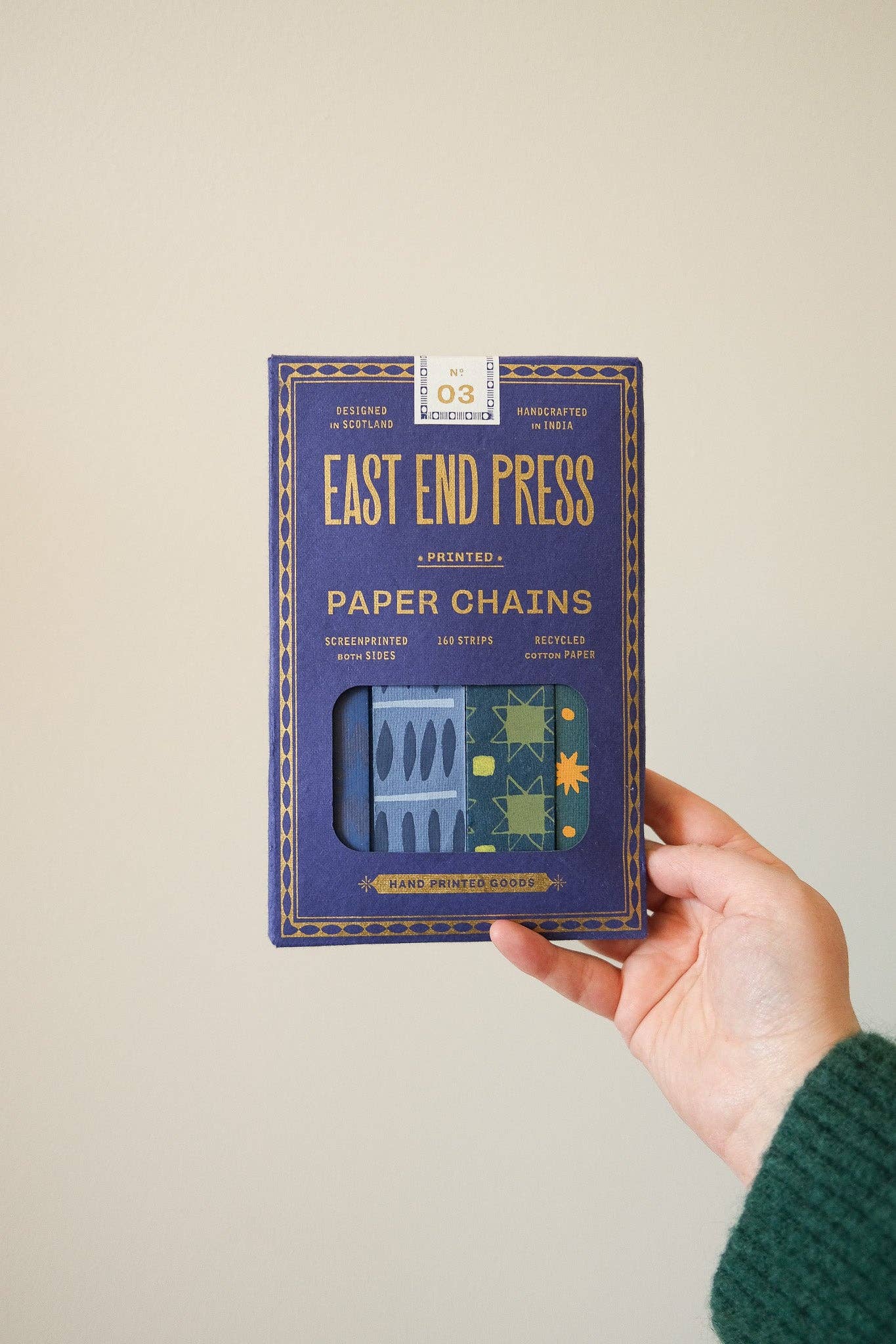 Hands demonstrating how to assemble a blue and yellow paper chain