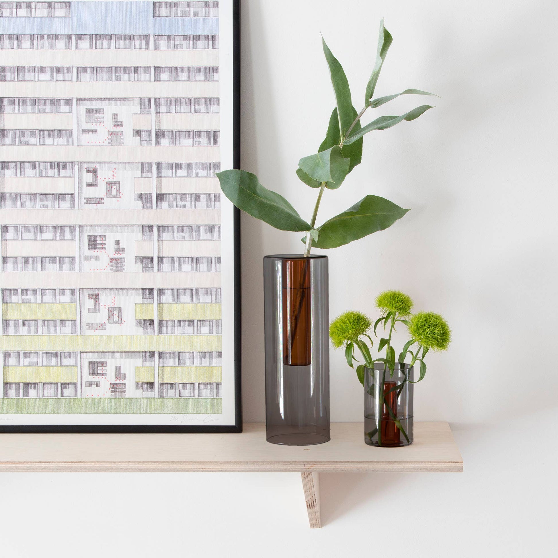 Decorative shelf with framed artwork and vases on a white wall background