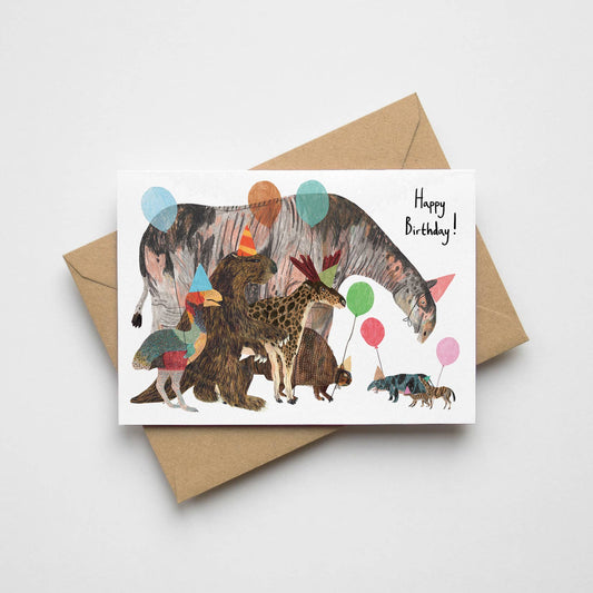 Hand-illustrated prehistoric birthday card featuring cartoon prehistoric mammals and a bird in party hats with balloons. A6 size, UK printed, blank inside.