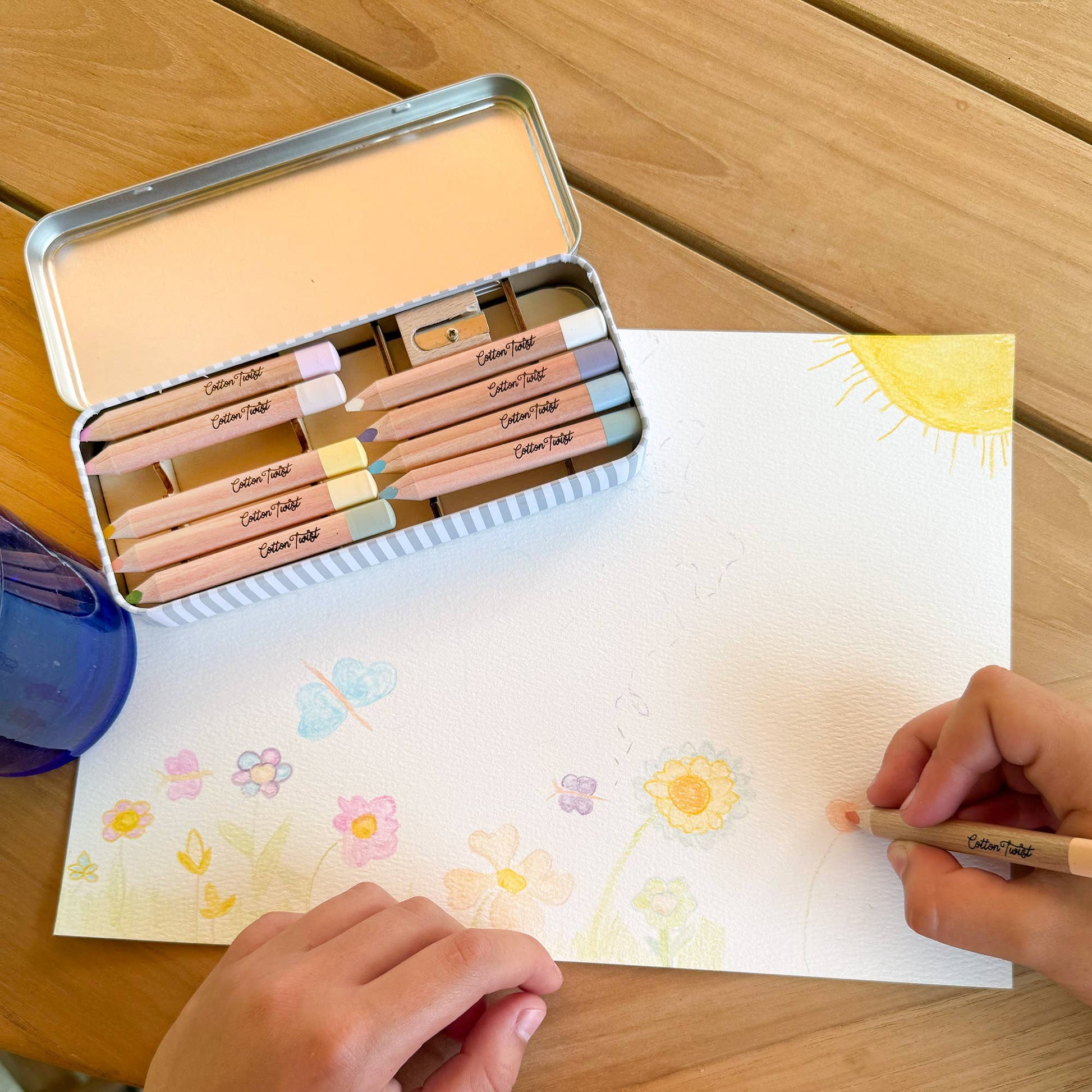 Colouring book with pencils and a tin on a wooden table