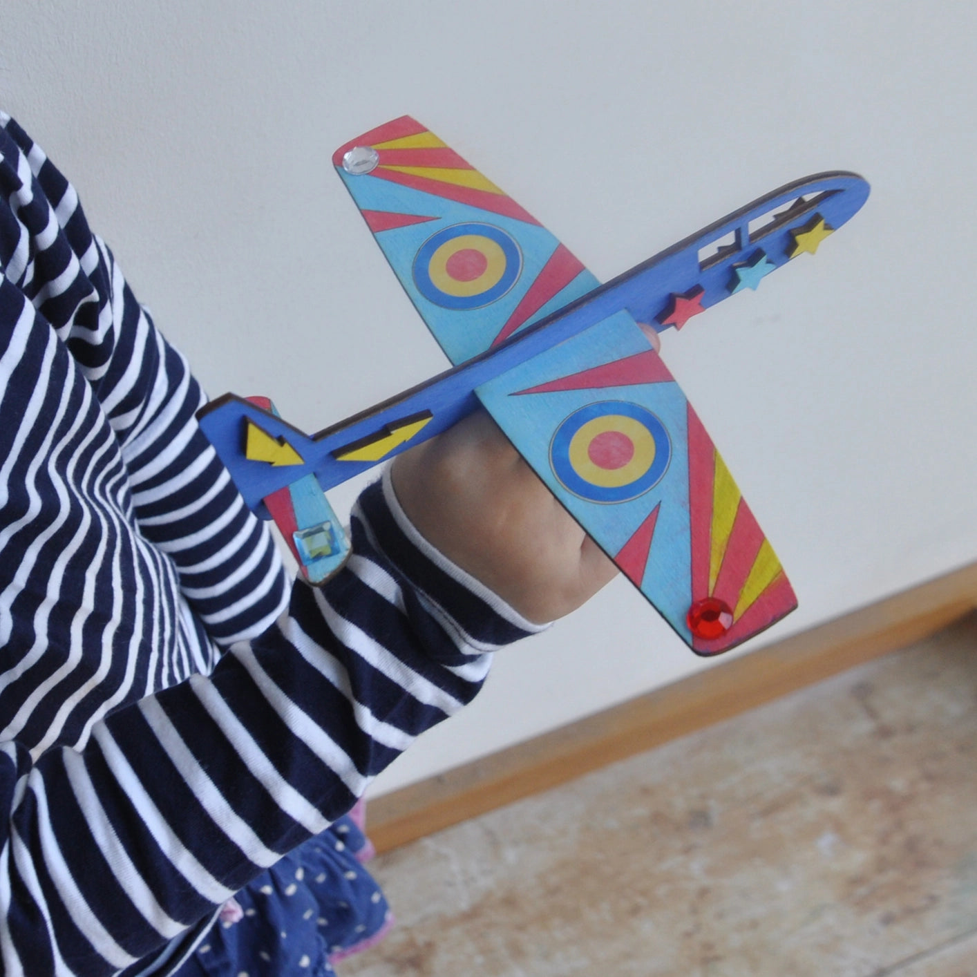 Finished wooden plane from the Cotton Twist craft kit, painted with colourful designs, ready for play.