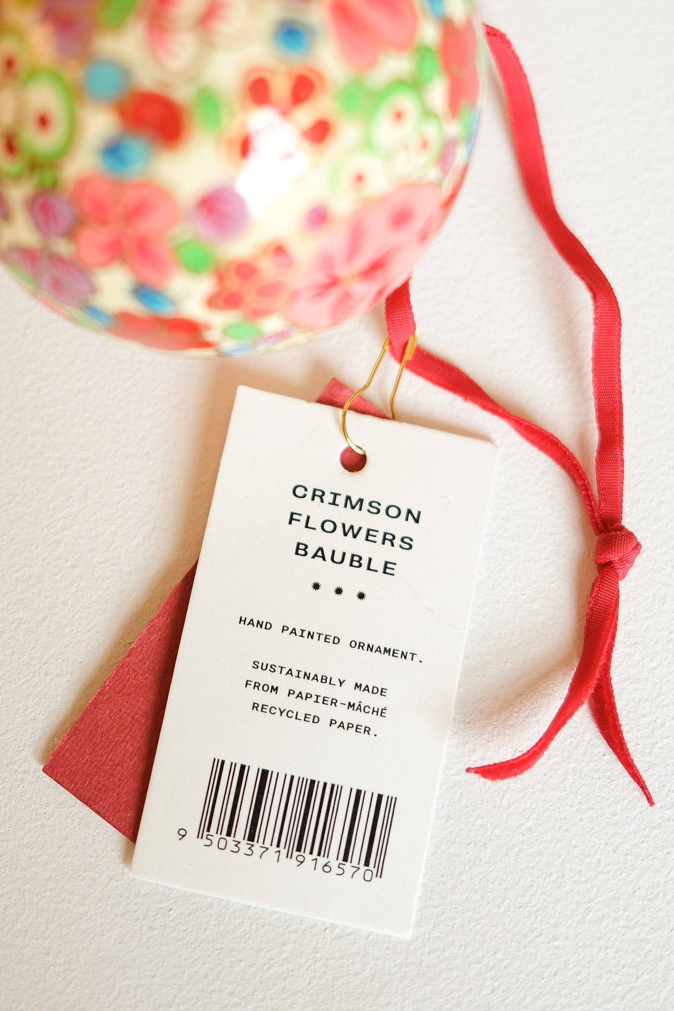 Crimson flower bauble hanging on a Christmas tree branch