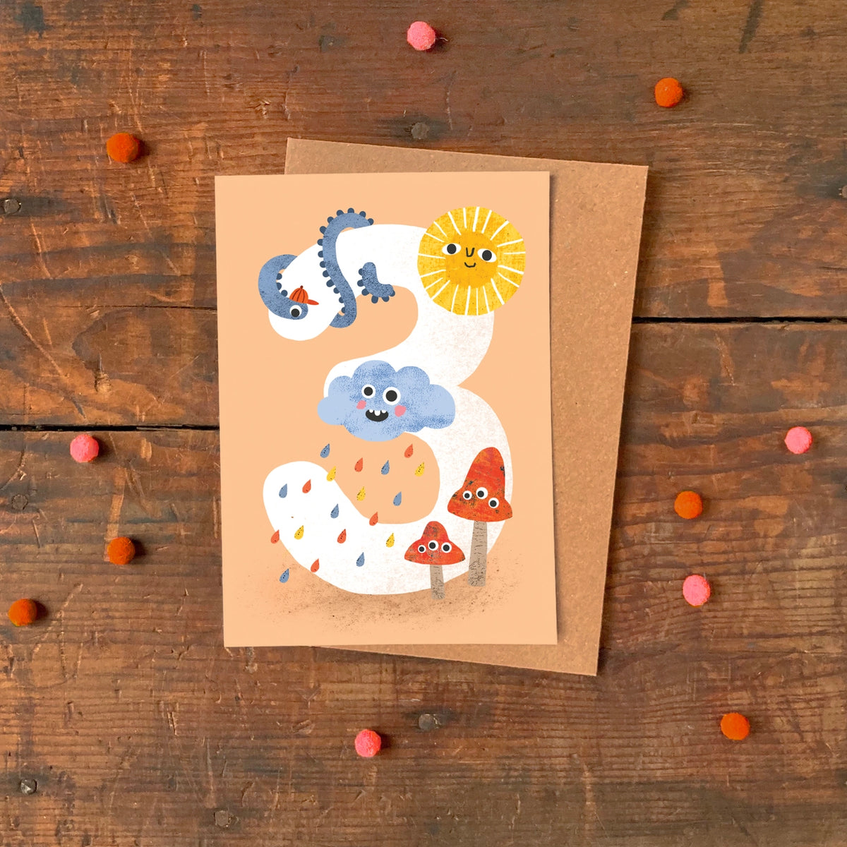 Age 3 birthday card with colourful cloud, sun, and mushroom illustrations on a peach background. Made in the UK.
