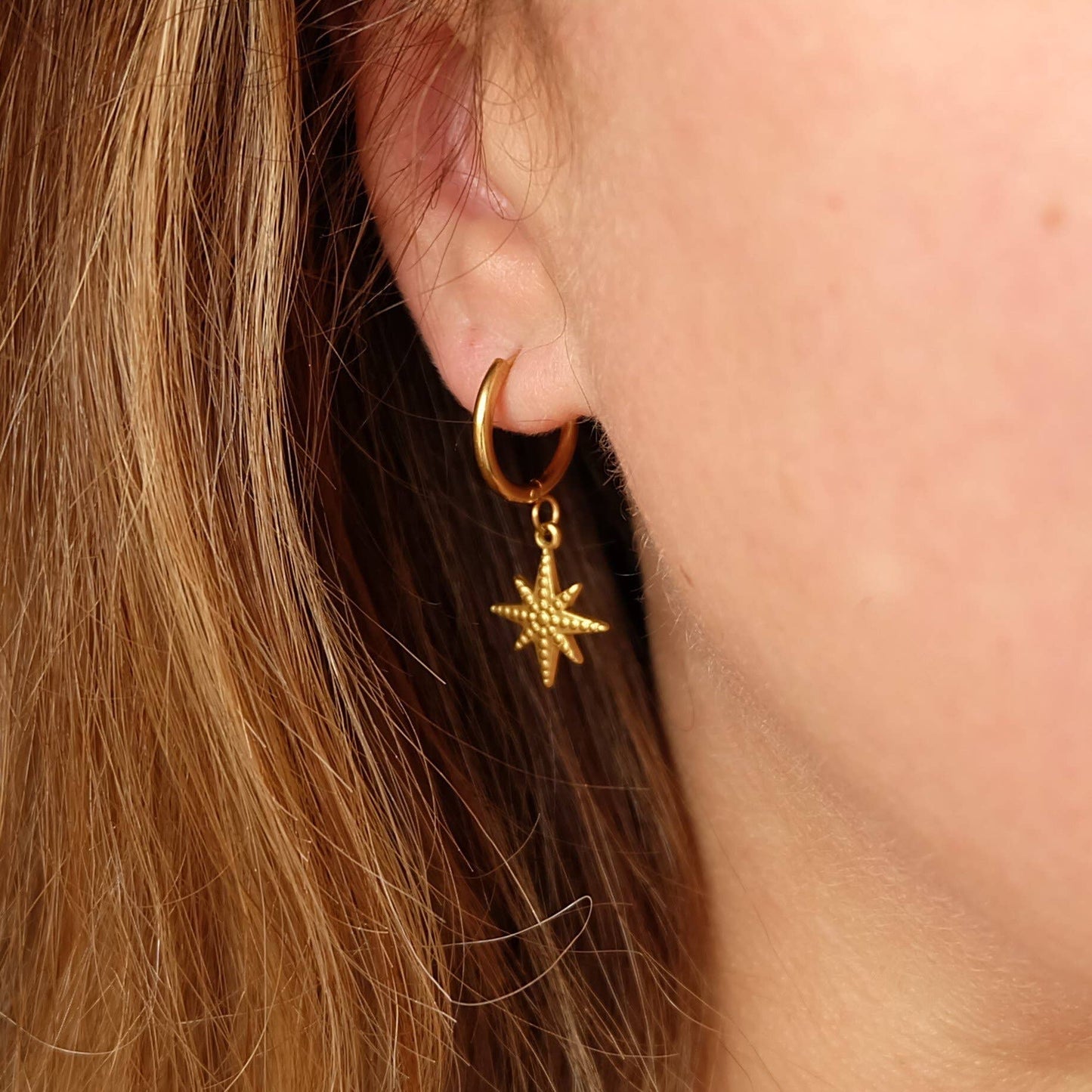 Close up of celestial star earrings in gold stainless steel