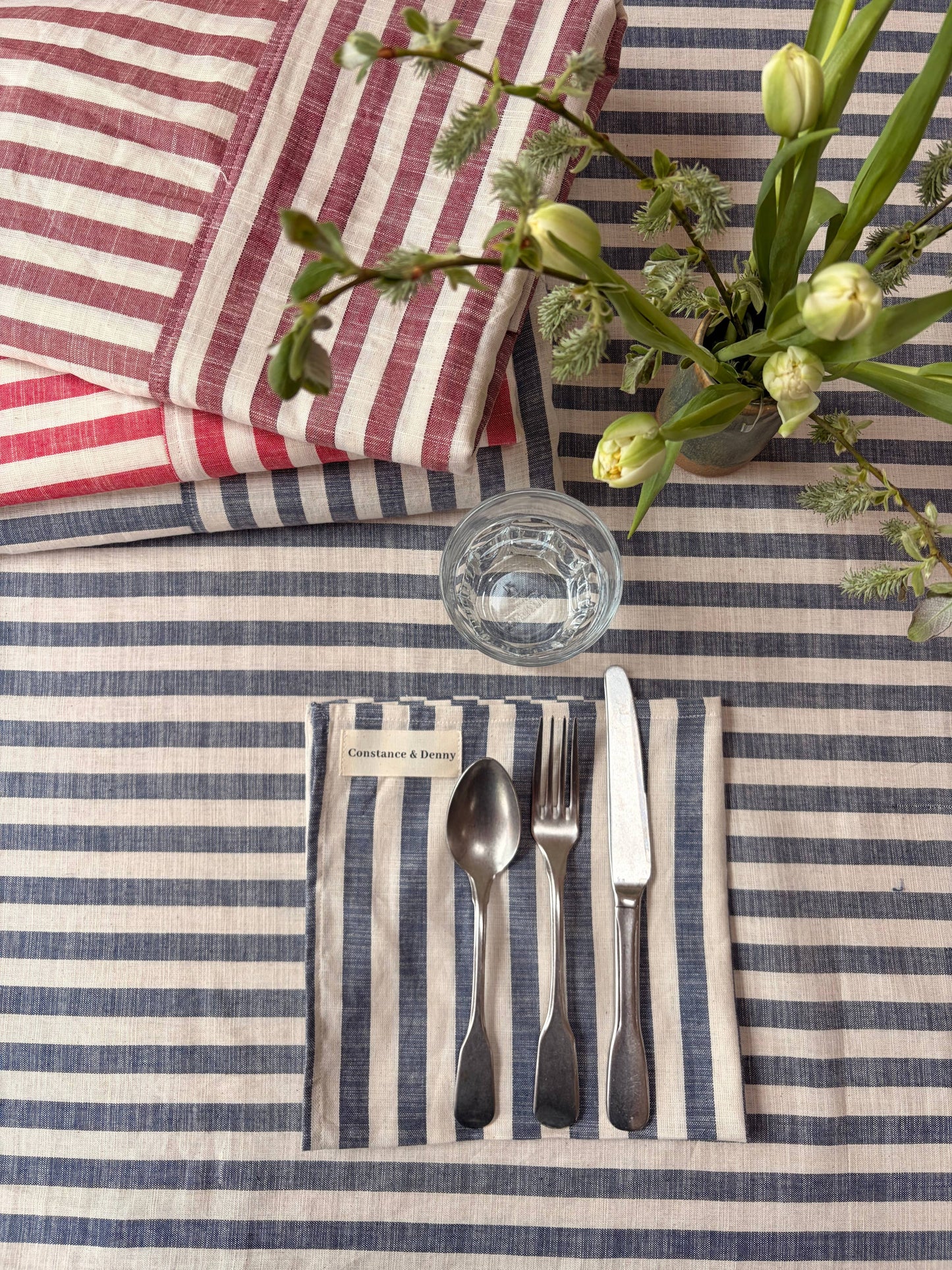 Set of four woven cotton napkins in indigo stripe laid out on a dining table