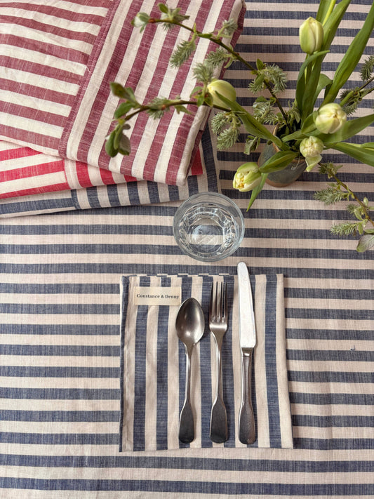Set of four woven cotton napkins in indigo stripe laid out on a dining table