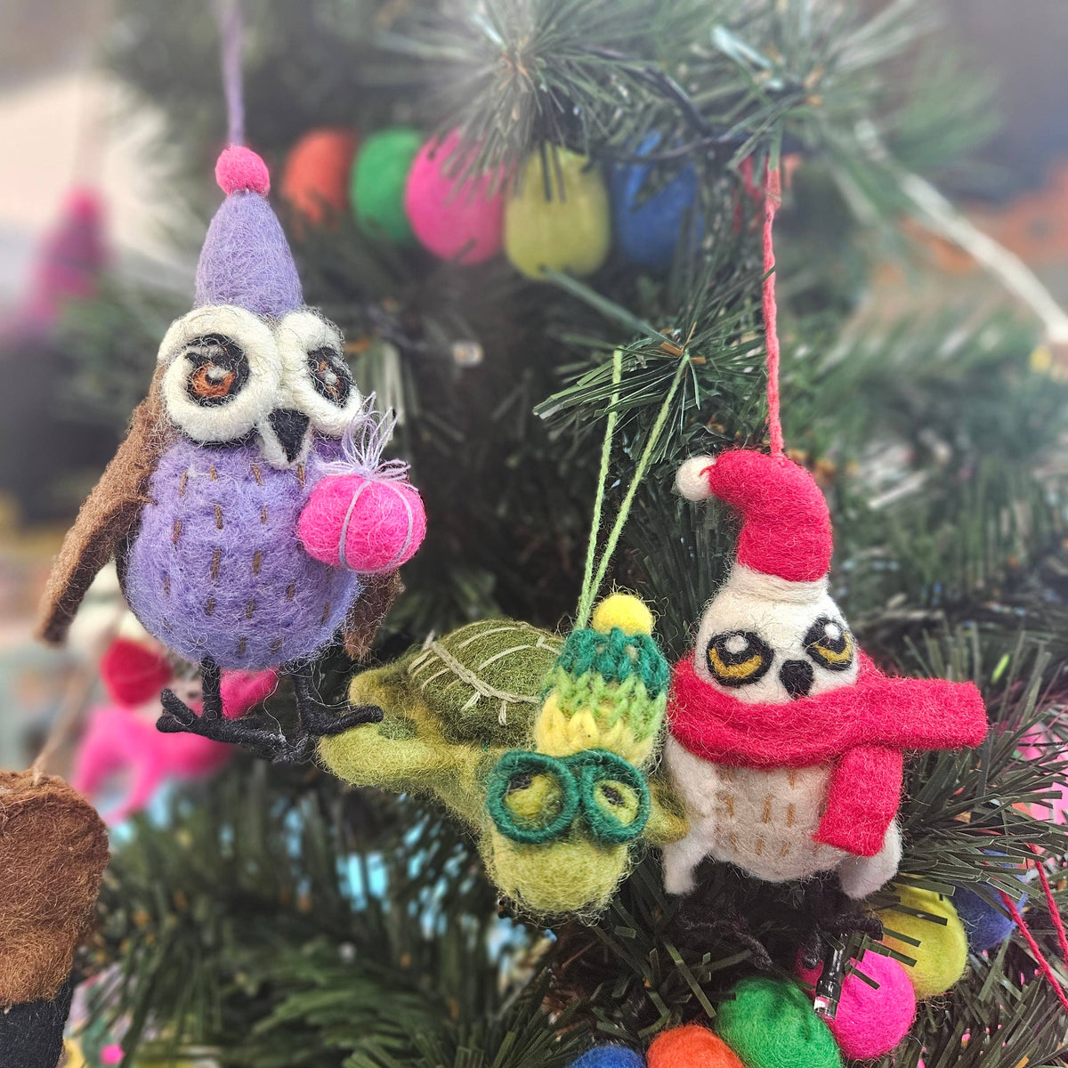 Fair trade felt snowy owl Christmas decoration hanging on a festive branch