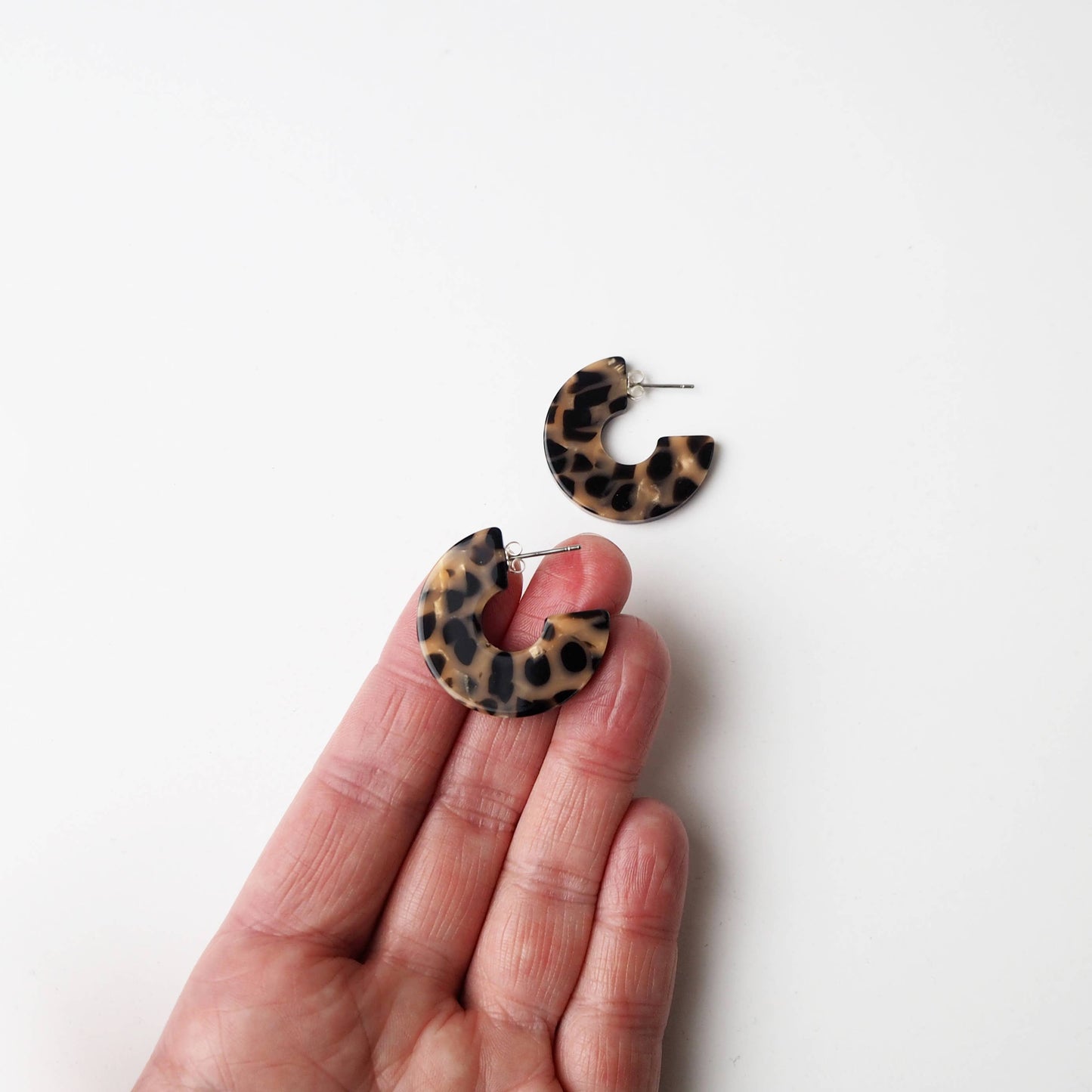Eco-friendly caramel and black resin hoop earrings on branded backing card