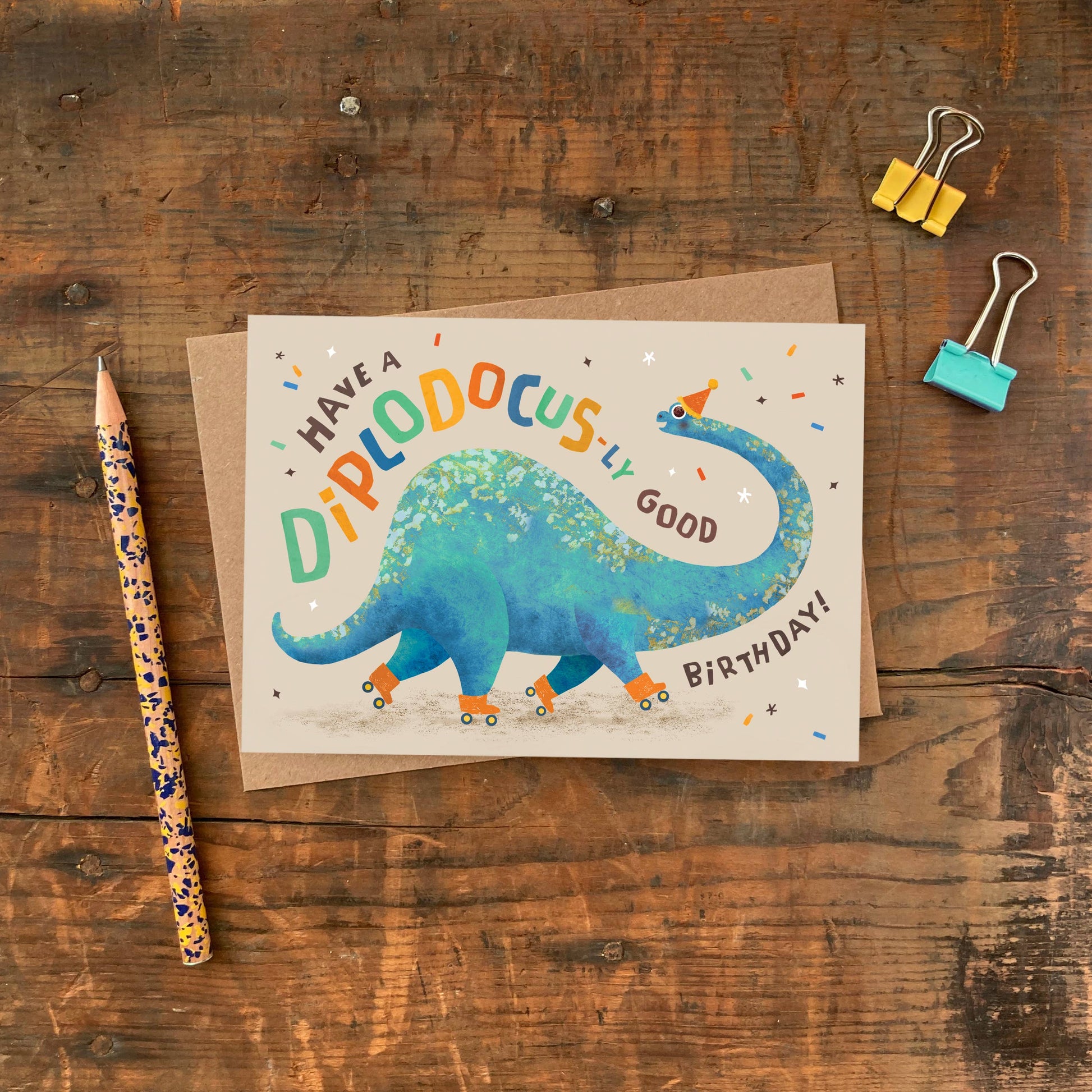 Diplodocus birthday card with recycled kraft envelope, showing the A6 size