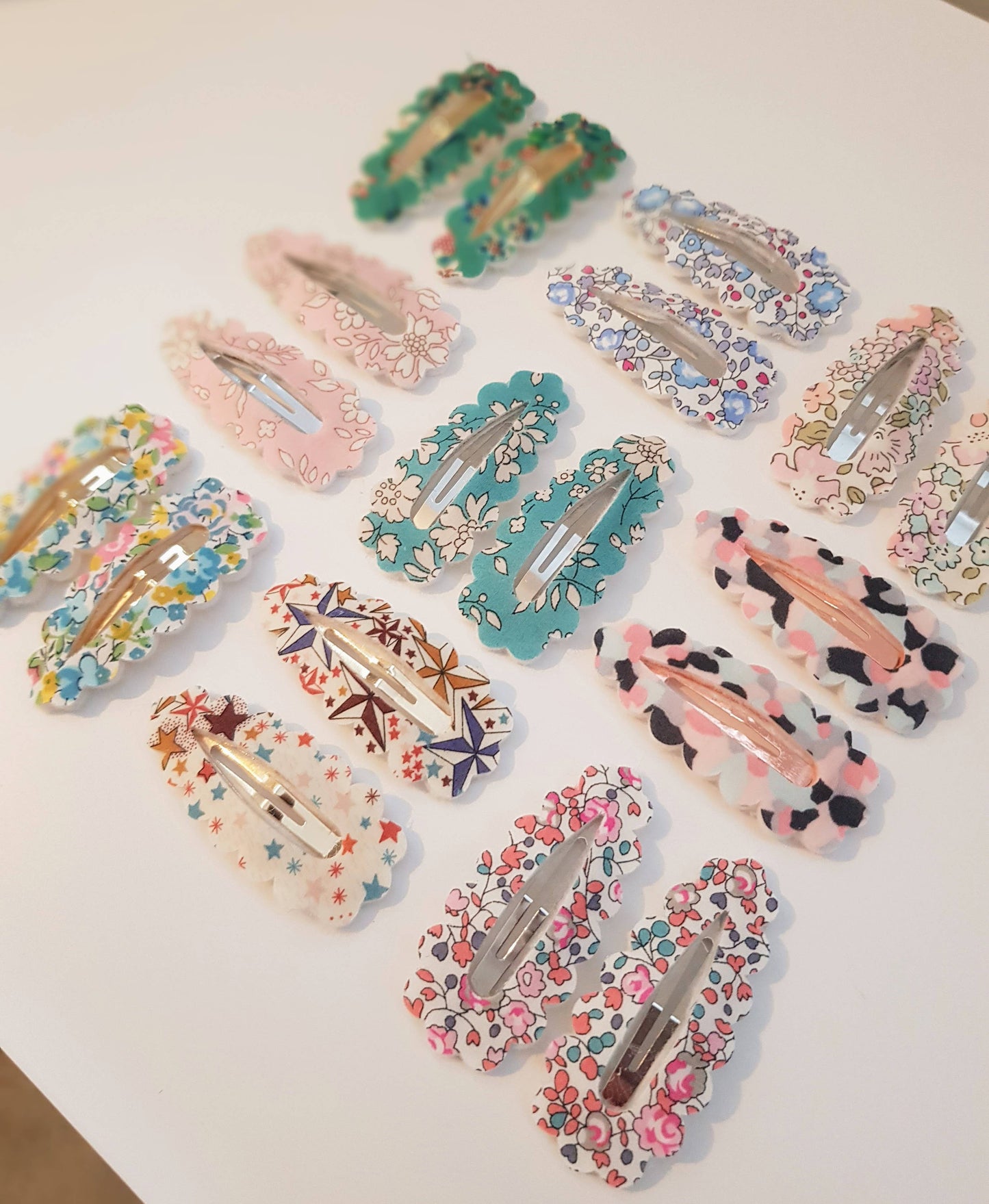Collection of colorful floral and patterned hair clips on a white surface