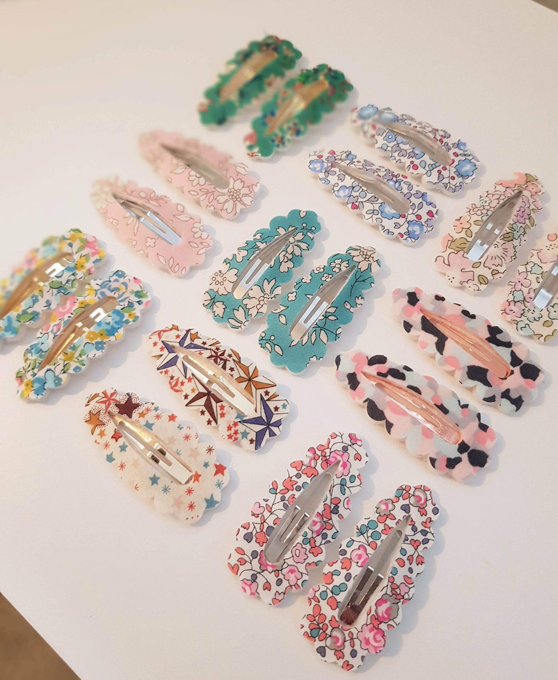 Collection of colorful floral and patterned hair clips on a white surface