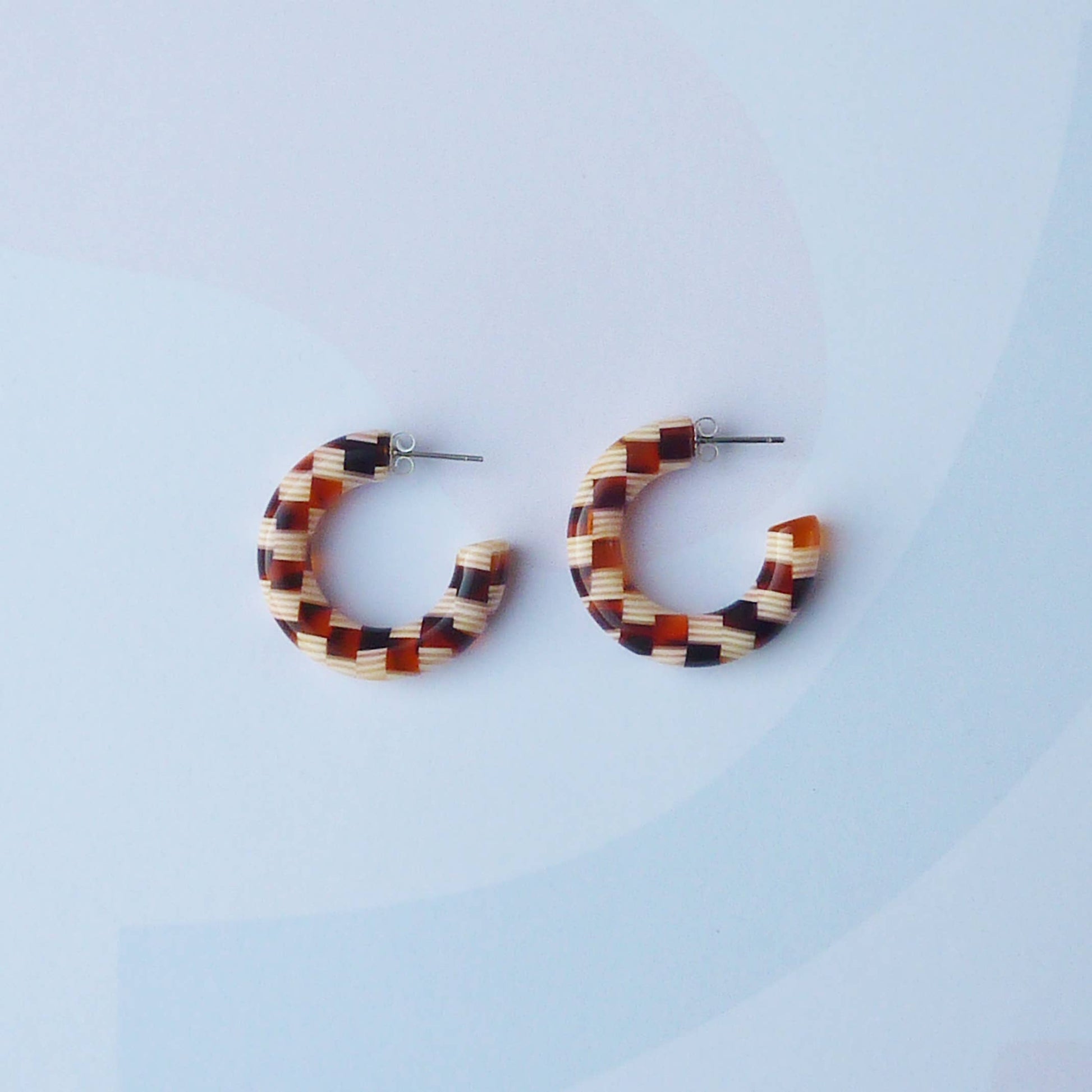 Honey checker acetate hoop earrings on a branded display card