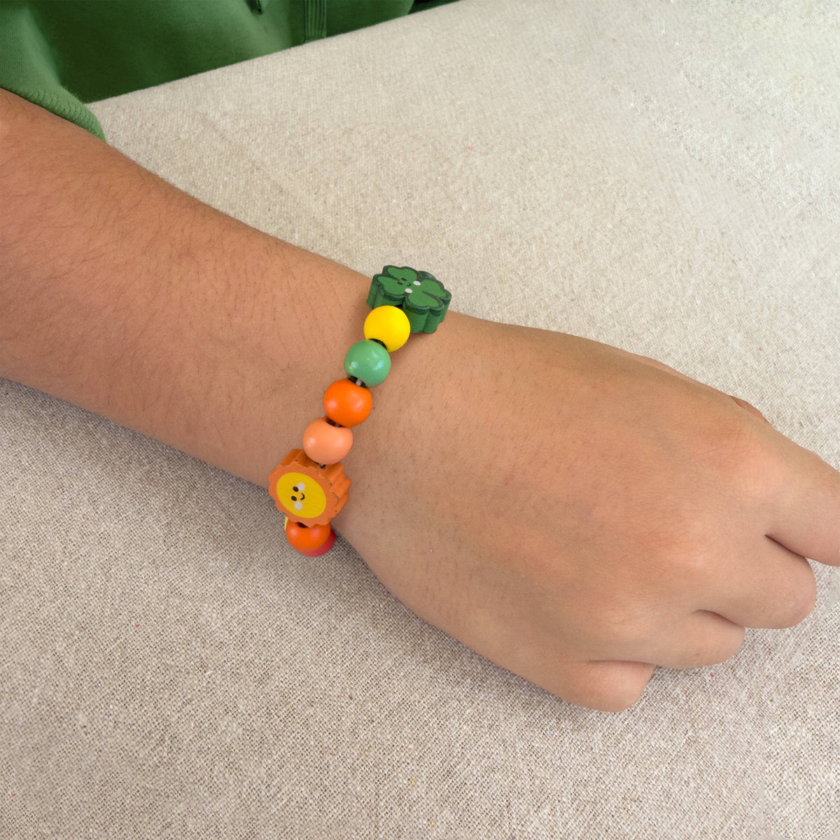 Child threading colourful wooden beads with easy thread elastic