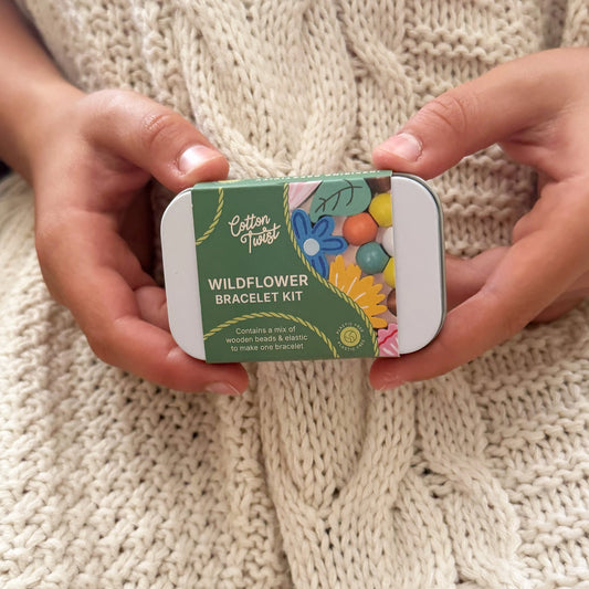 Wildflower bracelet making kit in a rectangular hinged tin, featuring wooden beads and elastic.