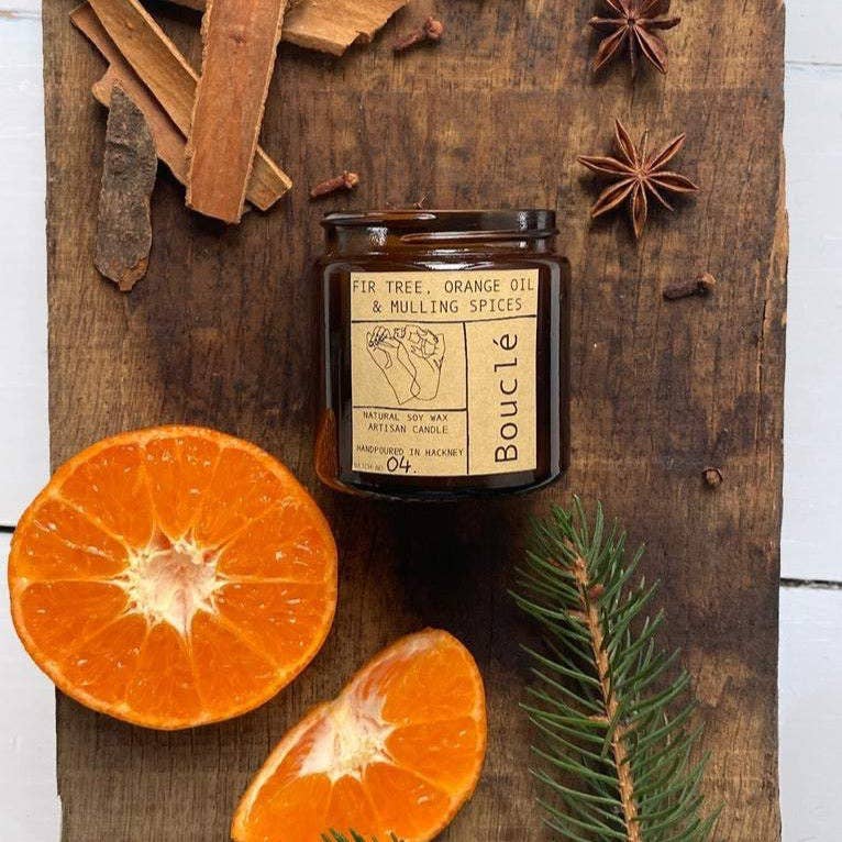 Festive winter candle with fir tree, orange, and mulling spices