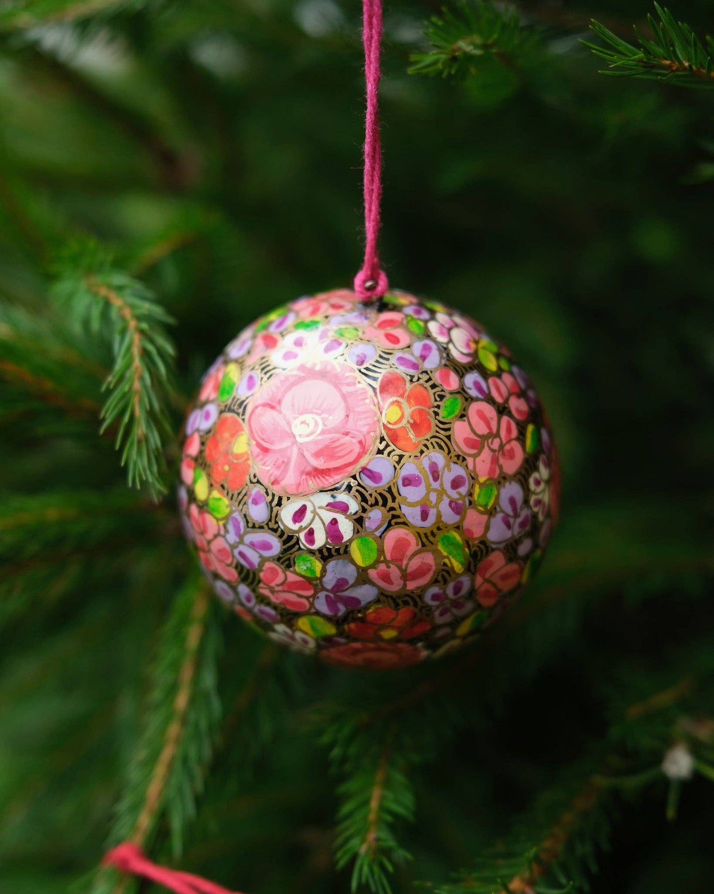 Detail shot of the hand-painted gold floret pattern on a Papier Mâché Christmas Bauble.