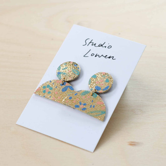 Close-up of pair of hand-painted floral drop leather earrings