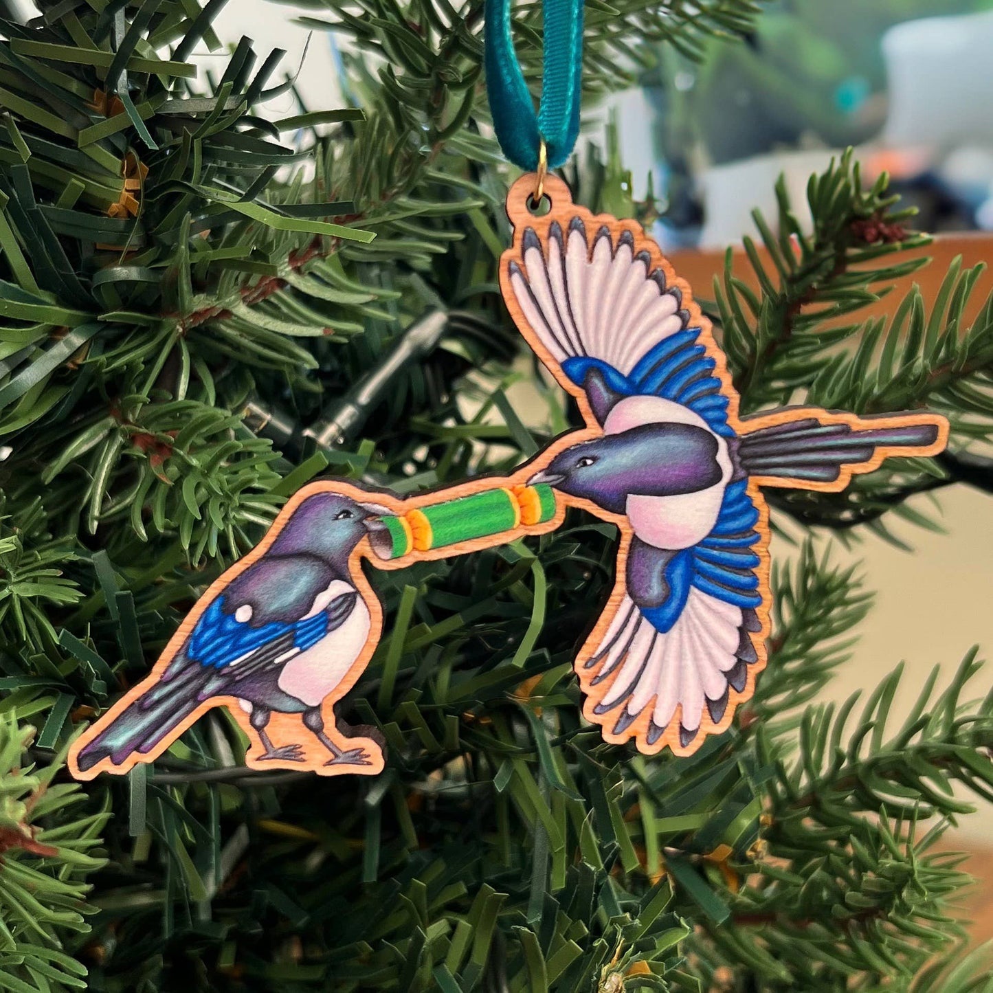Magpie wooden Christmas tree decoration featuring Teddy & Kipling illustration, sustainably certified cherry wood, gold-plated ring, and dark teal velvet ribbon