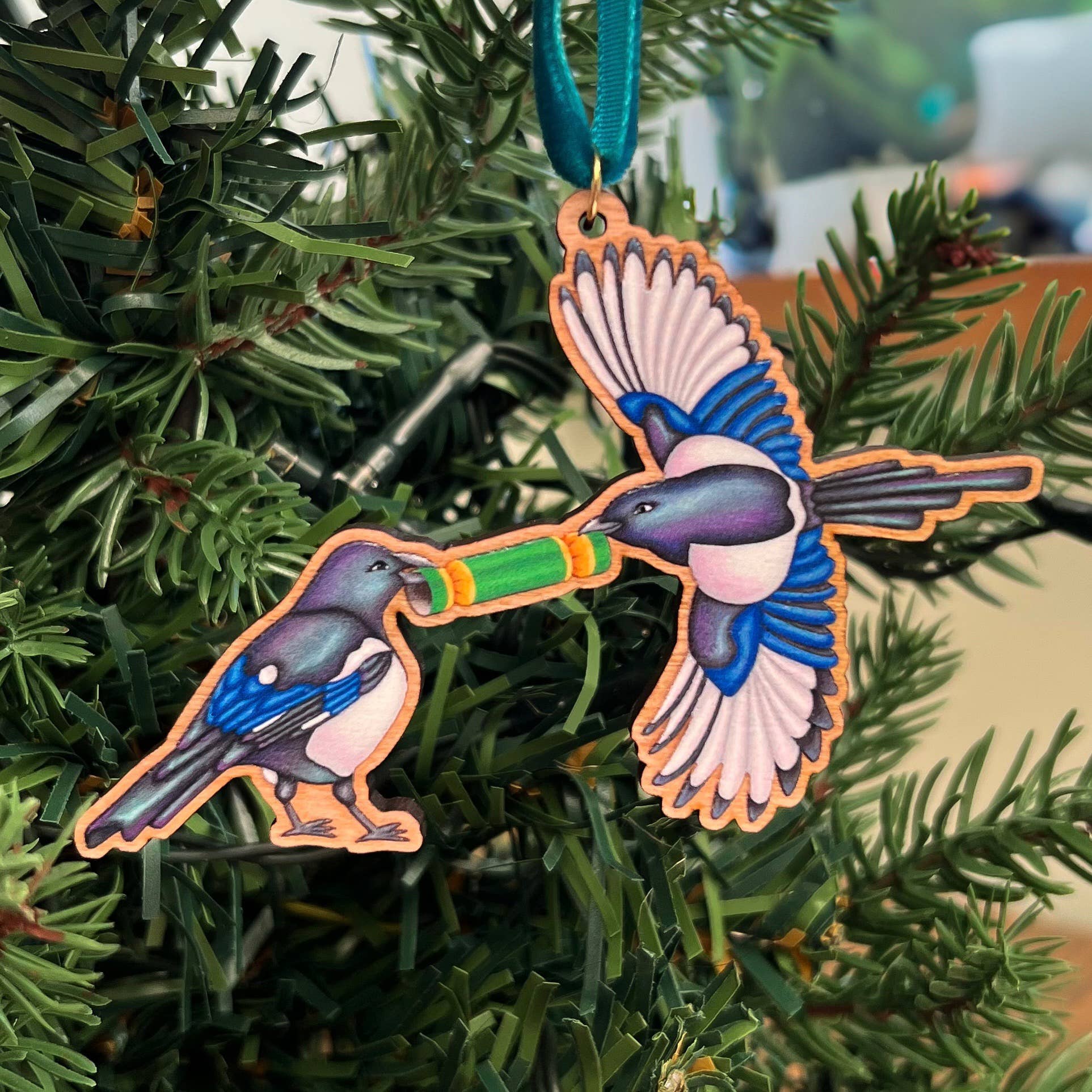 Magpie wooden Christmas tree decoration featuring Teddy & Kipling illustration, sustainably certified cherry wood, gold-plated ring, and dark teal velvet ribbon