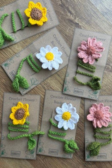Crocheted flower bookmark son cardboard backing with 'Crochet Flower Bookmark' text on a wooden surface.