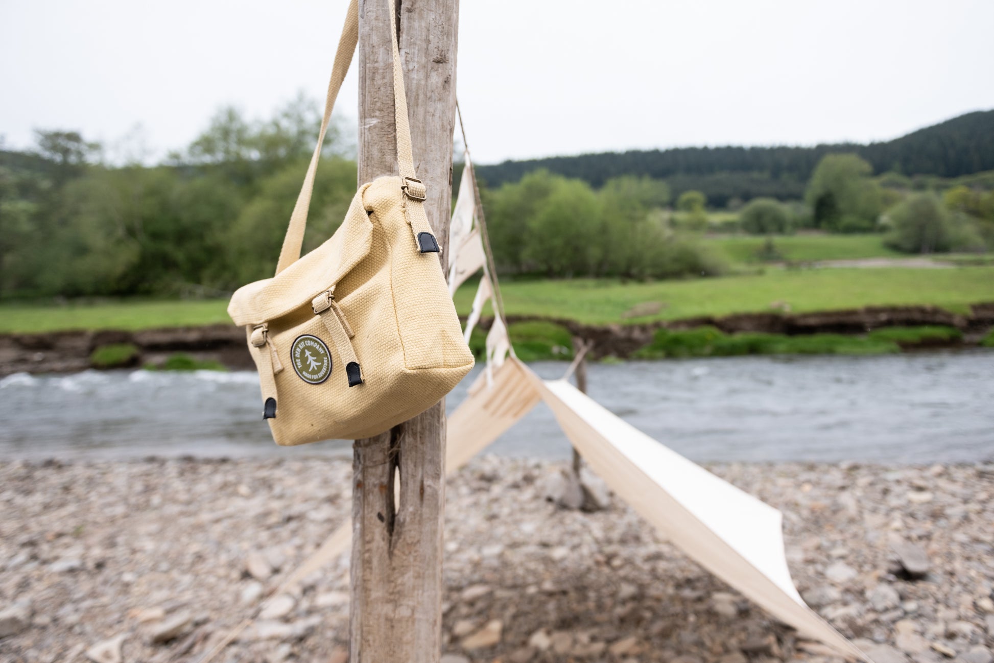 Pirate Den Kit including yellow cotton haversack, cotton calico tarpaulin, waterproof groundsheet, handmade wooden mallet, jute rope, steel tent pegs, pirate eye patch, and Jolly Roger bunting.