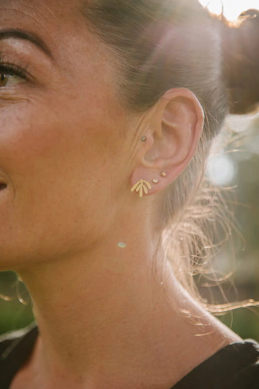 Model wearing a single Copper Bee brass leaf stud earring, showcasing its lightweight design and subtle botanical elegance.