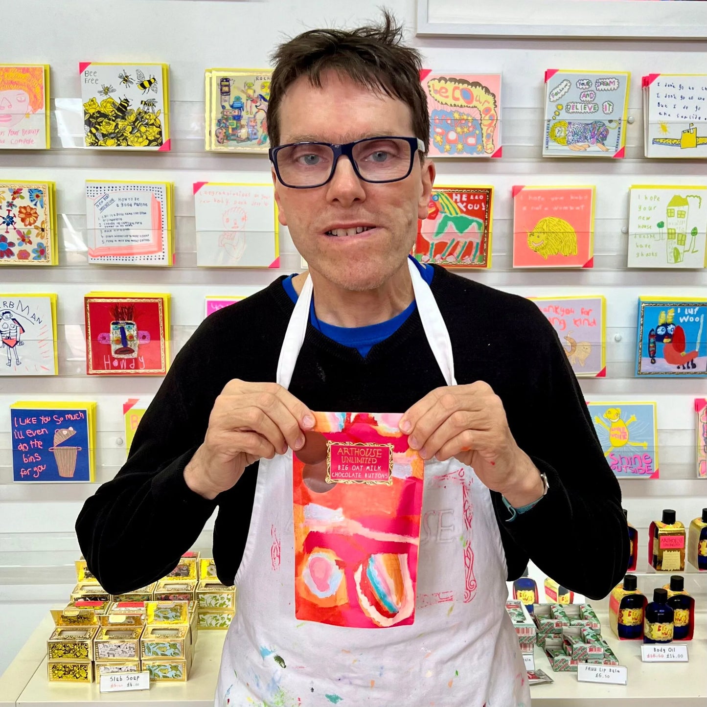 Person holding chocolate buttons in front of a colourful display of cards and items