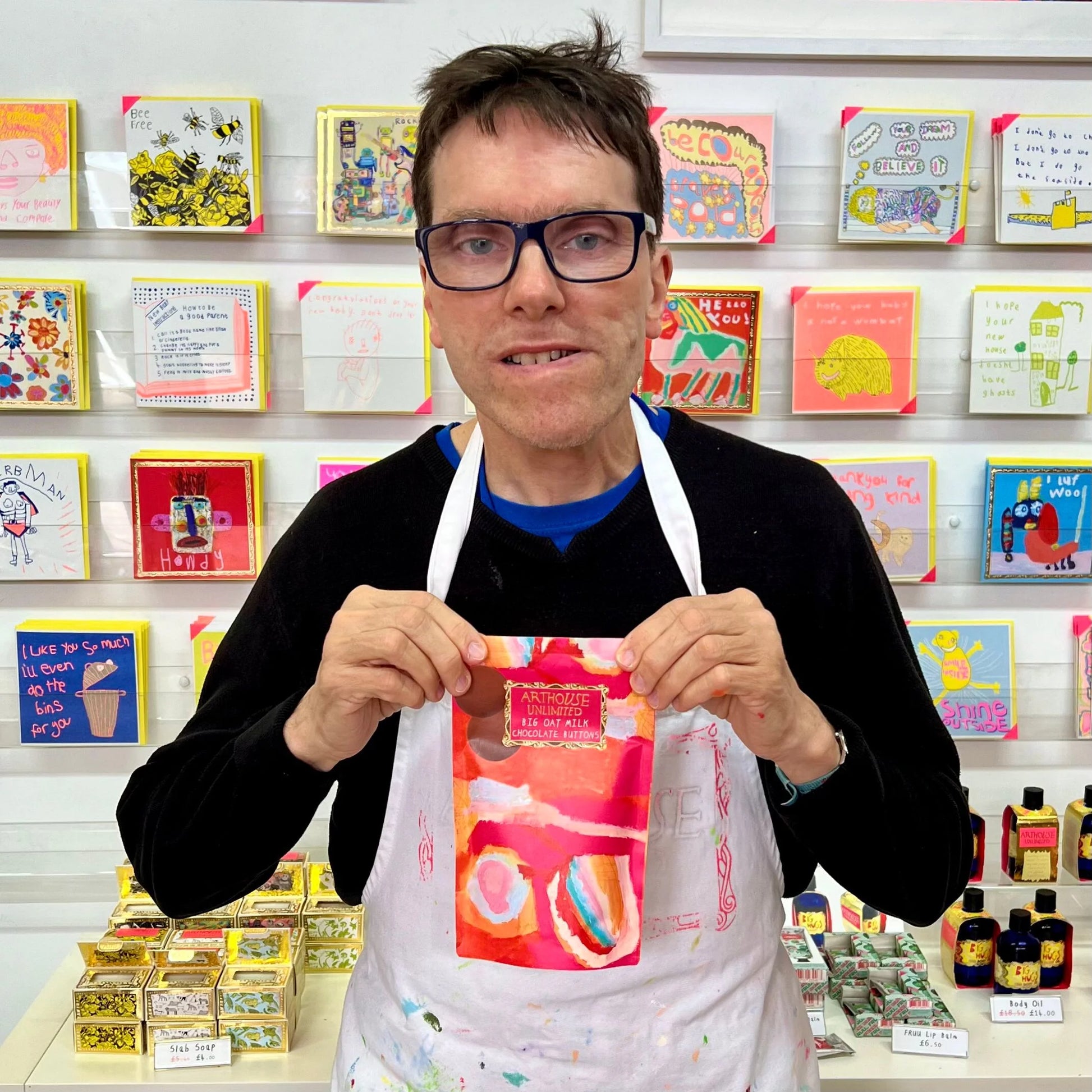 Person holding chocolate buttons in front of a colourful display of cards and items