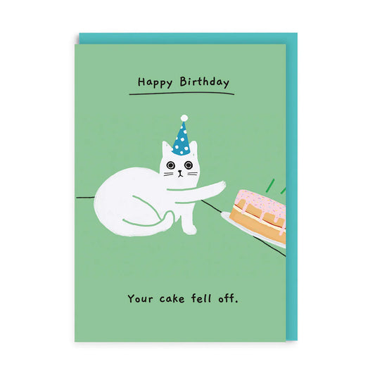 Illustrated green card with a nonchalant white cat in a party hat, pushing a birthday cake of the table with their paw. With the words Happy Birthday across the top of the card and Your cake fell off across the bottom.