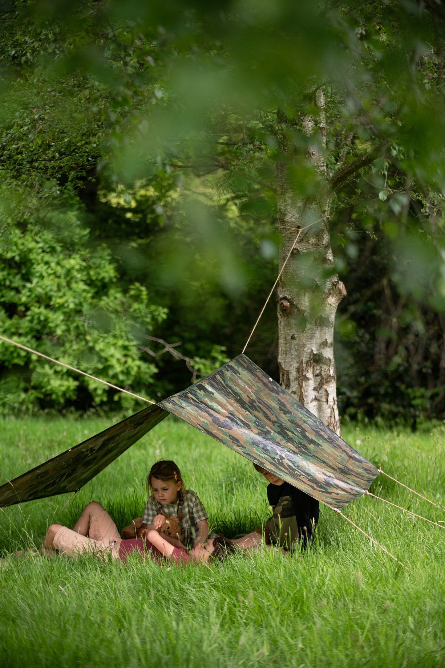 Children relaxing in the outdoors, in their den on the grass.