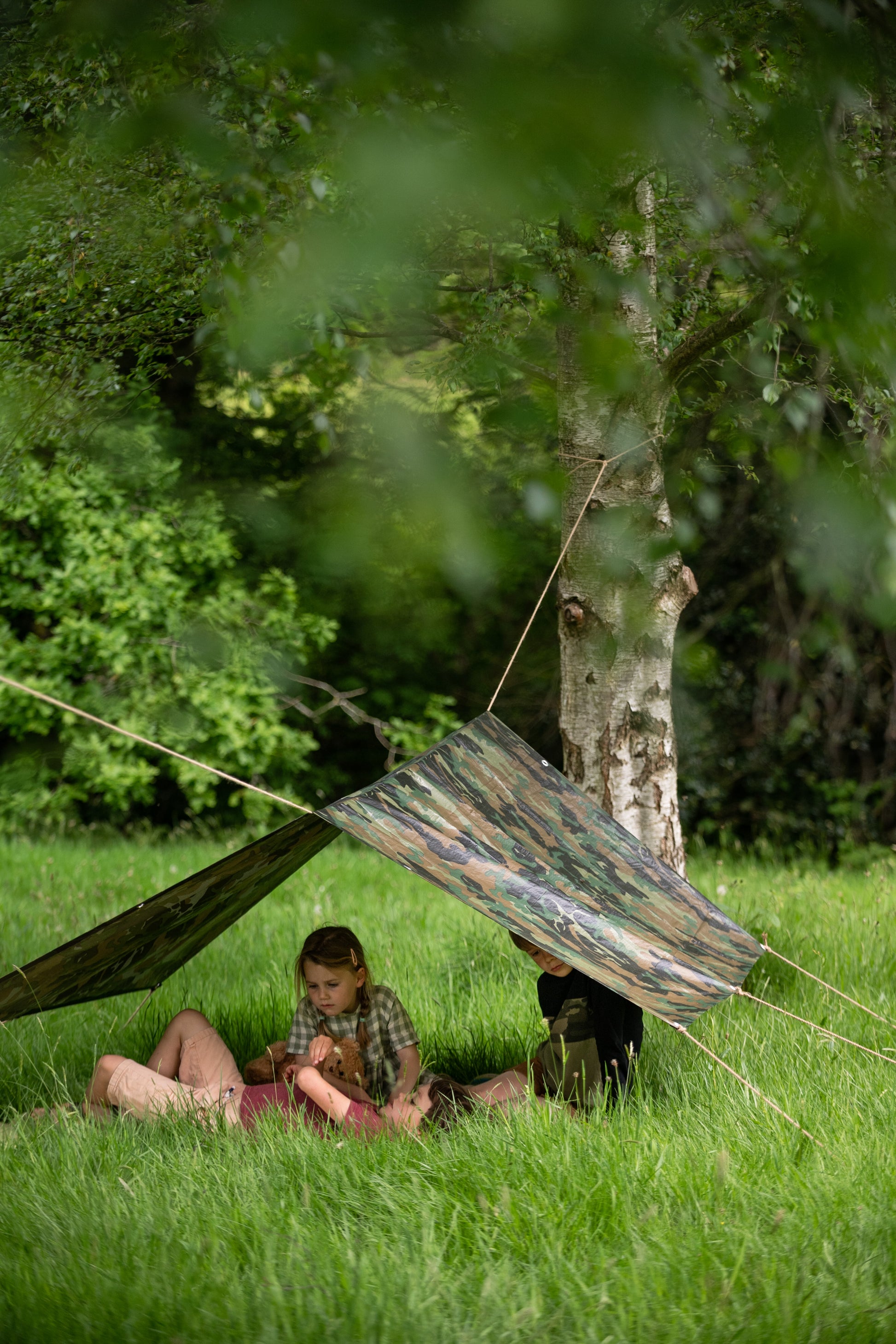 Children relaxing in the outdoors, in their den on the grass.