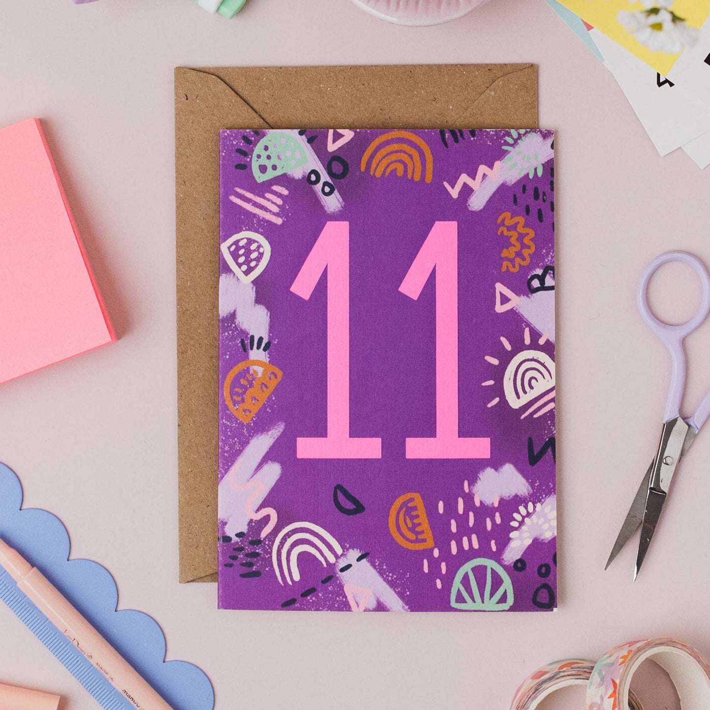 This on trend colour palette and neon pink number makes this milestone birthday card stand out on the shelf. Printed onto premium matt card with a kraft envelope. Illustrated greeting card with abstract shapes pattern and neon pink ink number 11.